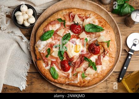 Pita pizza with prosciutto, pineapple, grilled tomatoes and egg on wooden table, flat lay Stock Photo
