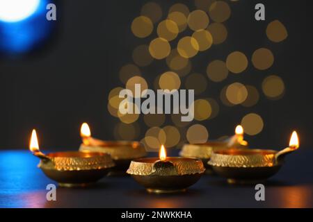 Lit diya lamps on dark table. Diwali celebration Stock Photo