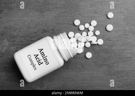 Plastic bottle with Amino Acid Complex and pills on grey background, flat lay Stock Photo