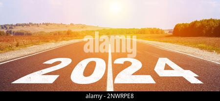 2024 written on highway road in the middle of empty asphalt road and beautiful blue sky. Concept for vision new year 2024. Stock Photo