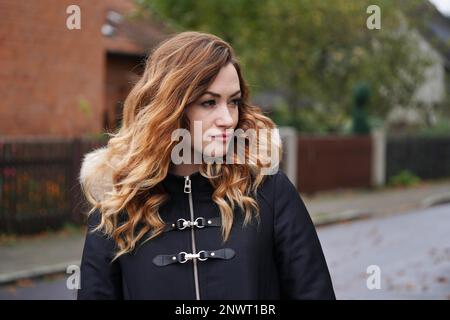 thoughtful young woman wearing winter coat on suburban street in Germany Stock Photo