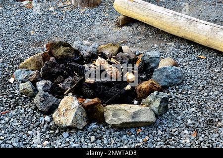 A circle of stones to enclose an outdoor campfire containing the burnt rements of last nights campfire. Stock Photo