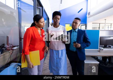 Diverse business people using tablet and discussing work at office. Working at office, business, finances and corporation concept. Stock Photo