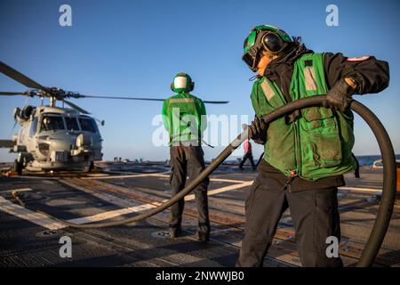 BALTIC SEA (Jan. 13, 2023) Aviation Machinist’s Mate Airman Majorie Rogero, assigned to Helicopter Maritime Strike Squadron (HSM) 79, removes a power cable from a MH-60R Seahawk helicopter on the flight deck of the Arleigh Burke-class guided-missile destroyer USS Roosevelt (DDG 80), Jan. 13, 2023. Roosevelt is on a scheduled deployment in the U.S. Naval Forces Europe area of operations, employed by U.S. Sixth Fleet to defend U.S., allied and partner interests. Stock Photo