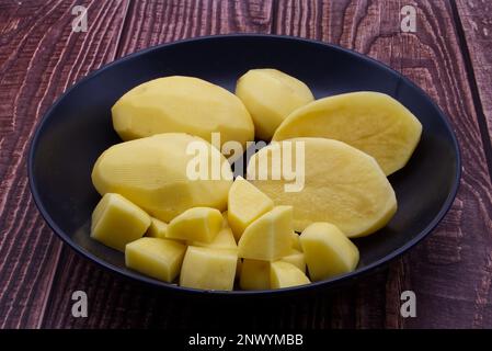 Peeled potatoes in a bowl on wooden table Stock Photo