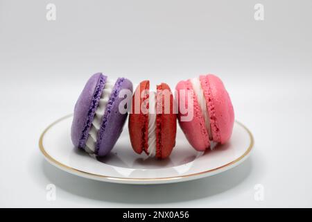 This image shows a close-up view of colorful French macaron confections with a cream filling, on a white background. Stock Photo