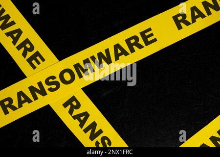 Ransomware cybercrime alert, caution and warning concept. Yellow barricade tape with word in dark black background. Stock Photo