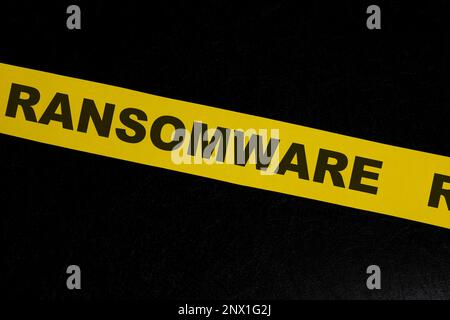 Ransomware cybercrime alert, caution and warning concept. Yellow barricade tape with word in dark black background. Stock Photo