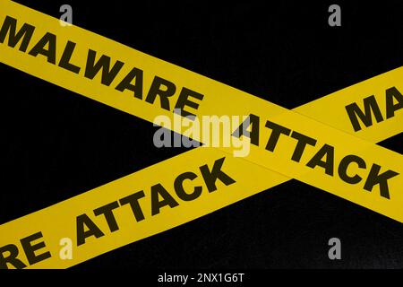 Malware attack cybercrime alert, caution and warning concept. Yellow barricade tape with word in dark black background. Stock Photo