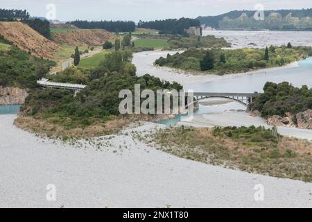 A wide landscape view of the Rakaia river at low water levels and a bridge over it in New Zealand. Stock Photo
