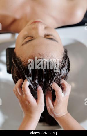 Young woman having her hair washed in beauty salon Stock Photo