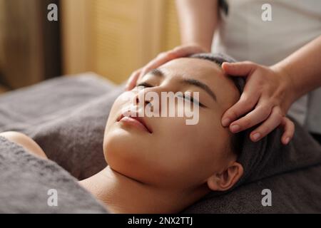 Two Asian men smiling and holding cloud and arrow icons while sitting at desk in office Stock Photo