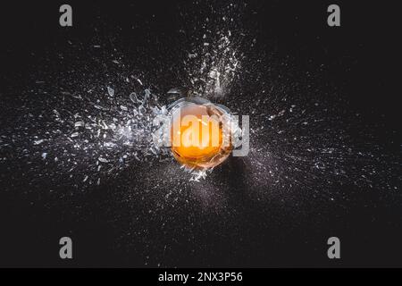 Explosion of glass ball and egg yolk on black background Stock Photo