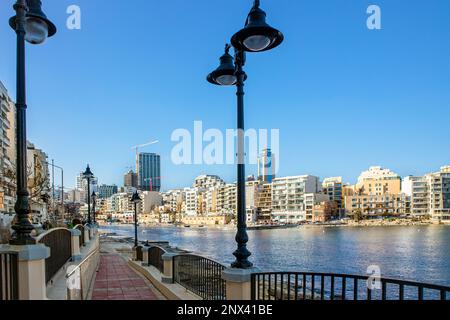 Spinola bay in Malta. Beautiful bay view with bay, buildings and boats, seen from pedestrian walkway on sunny spring evening. Stock Photo