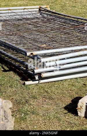 Metal fence mesh folded on the grass close up Stock Photo