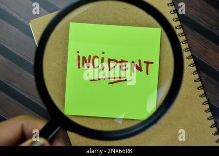 Concept of Incident write on sticky notes magnifying glass isolated on Wooden Table. Stock Photo