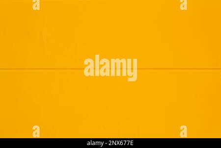 Yellow background. Solid color with a horizontal line in the middle. Picture taken from a metal door painted with yellow color on a sunny day. Stock Photo