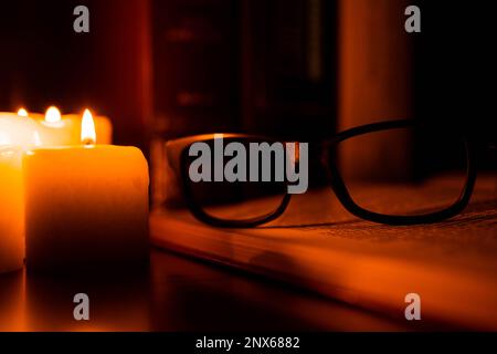 Still life of old books illuminated by a set of candles. Reading, Book Day, love of books Stock Photo