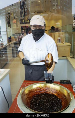 A young Asian American makes a boba milk drink in the window at Xing Fu Tang, a Taiwanese store on Main St. in Flushing, Queens, New York's Chinatown. Stock Photo