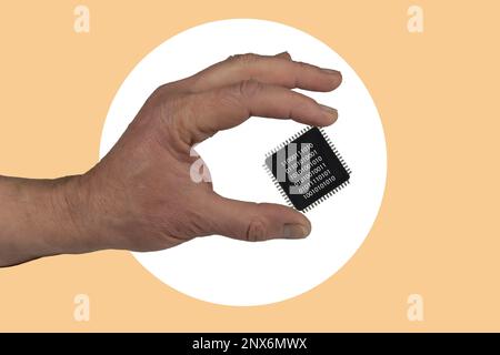 The hand holds the microprocessor with digital code. Art collage. Stock Photo