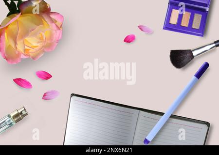 Feminine workspace: blank open notepad, pen, cosmetic accessories. Pink rose and petals on pink background. Top view. Stock Photo