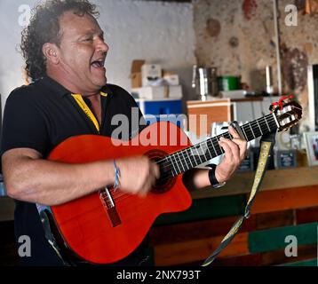 Man playing guitar and singing indoors Stock Photo