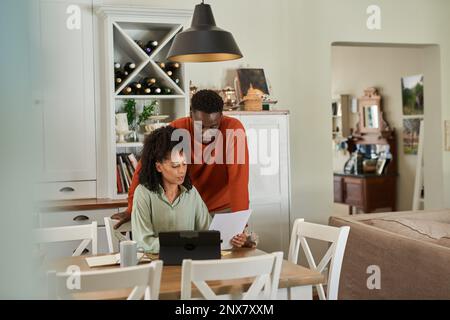Young multiracial couple paying bills online at home Stock Photo
