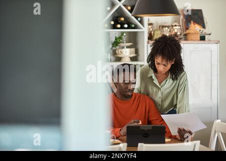 Young multiracial couple doing their online banking on a tablet Stock Photo