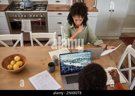 Multiracial couple working remotely from home at a kitchen table Stock Photo