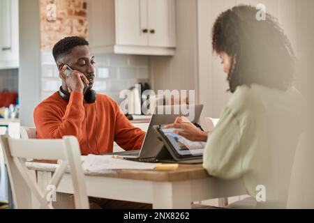 Young multiracial couple working online remotely at their kitchen Stock Photo