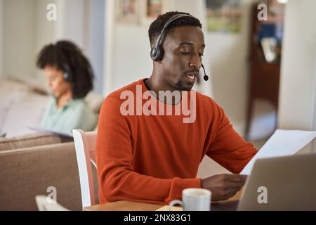 Young African man on a call while working remotely from home Stock Photo