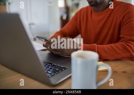 African businessman texting on his phone while working from home Stock Photo