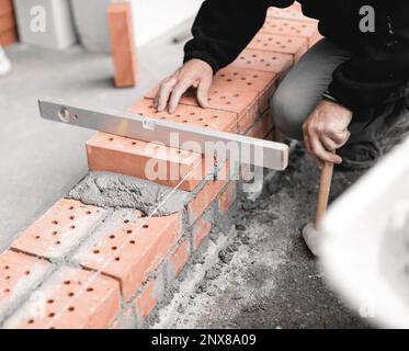handyman checking the surface level of the brick wall with the spirit level Stock Photo