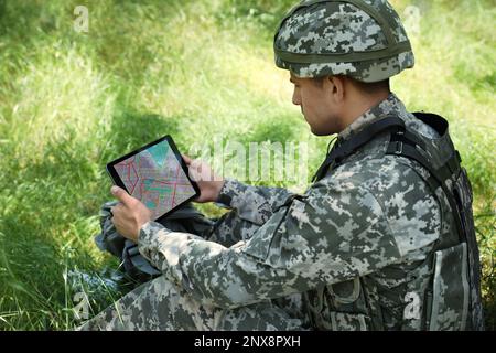 Soldier with backpack using tablet in forest Stock Photo