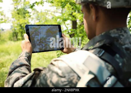 Soldier using tablet in forest. Modern technology Stock Photo