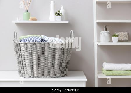 Wicker basket with dirty laundry on table indoors Stock Photo