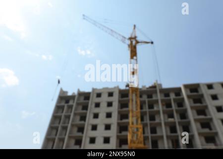 Blurred view of unfinished building and construction crane outdoors Stock Photo