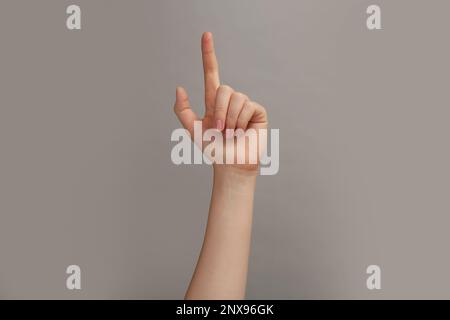 Woman showing index finger on grey background, closeup Stock Photo