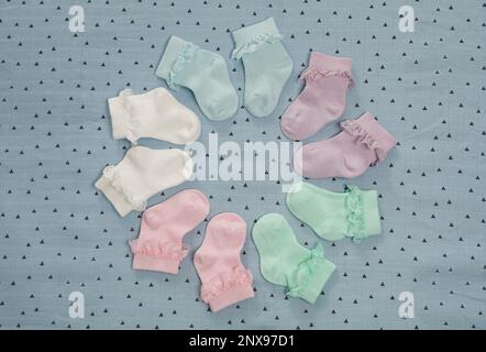 Many colorful baby socks on light blue fabric, flat lay Stock Photo