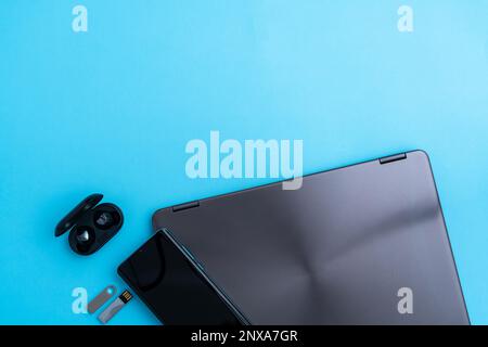 Laptop with mobile phone headphones and flash drives as digital technology concept Stock Photo