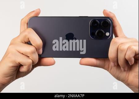 New york, USA - February 24, 2023: Rear view of iphone pro in hands isolated on white studio background Stock Photo