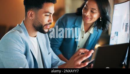 Man, woman and tablet in office at night for analytics, research and information technology with teamwork. Businessman, web design discussion and Stock Photo