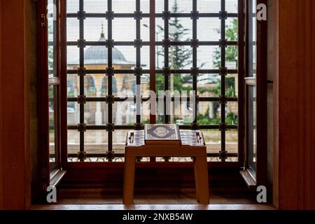 Selective focus, the holy book of the Muslims, the Koran, on the reading table by the barred window. Stock Photo