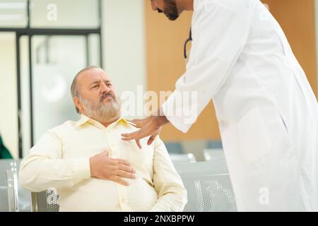 An elderly male patient with high body fat, obesity, sees a doctor at the hospital due to body problems because of a lot of weight. Stock Photo