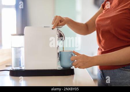 Unrecognizable Woman Turning On Coffee Machine While Preparing Morning Drink In Kitchen Stock Photo
