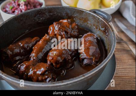 Beef roulades with brown sauce, red cabbage and potato dumplings on wooden table Stock Photo