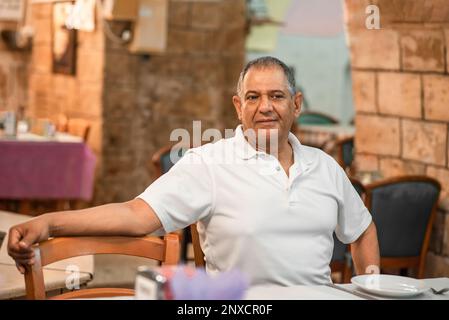 Portrait middle eastern senior man sitting in a restarant and looking in camera. Stock Photo