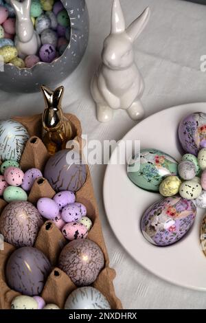 photo of painted eggs lying on the table with a white ceramic rabbit next to them Stock Photo