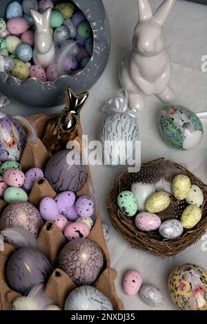 photo of painted eggs lying on the table with a white ceramic rabbit next to them Stock Photo