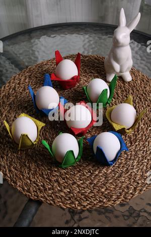 photo of a white rabbit and eggs in colorful packages standing on a glass table Stock Photo